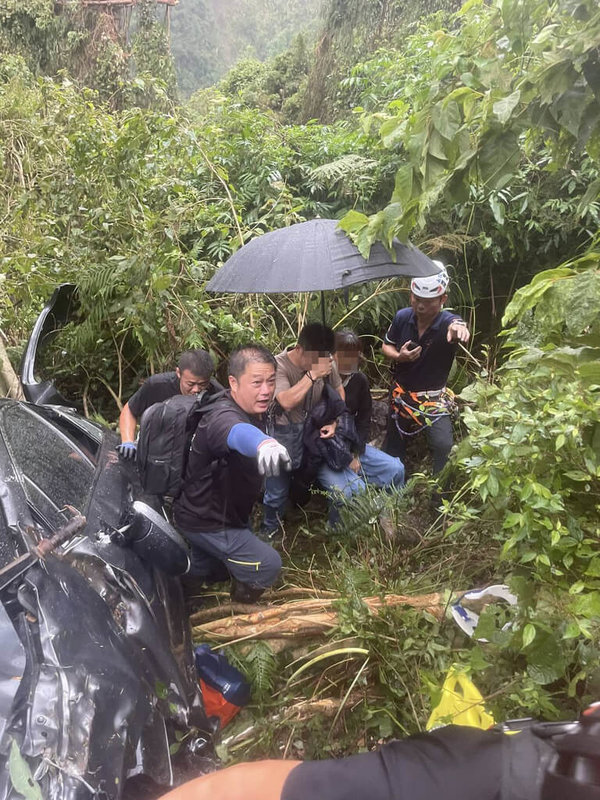 南投縣信義鄉台21線123公里處附近23日發生汽車墜谷意外,車輛被樹木擋住,卡在至少200公尺深處,車內4人受困。消防人車到場救出受困者,4人皆意識清醒、送醫治療。(南投縣消防局提供)中央社記者蕭博陽南投縣傳真 114年8月23日