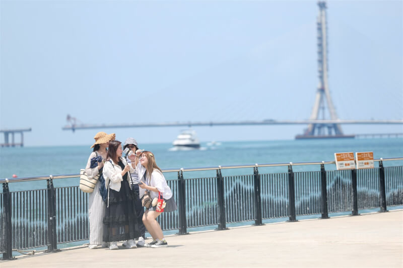 交通部中央氣象署24日下午發布高溫資訊,雙北已出現攝氏38度以上高溫。圖為出遊民眾在淡水河畔拍照留念。中央社記者吳家昇攝 114年8月24日
