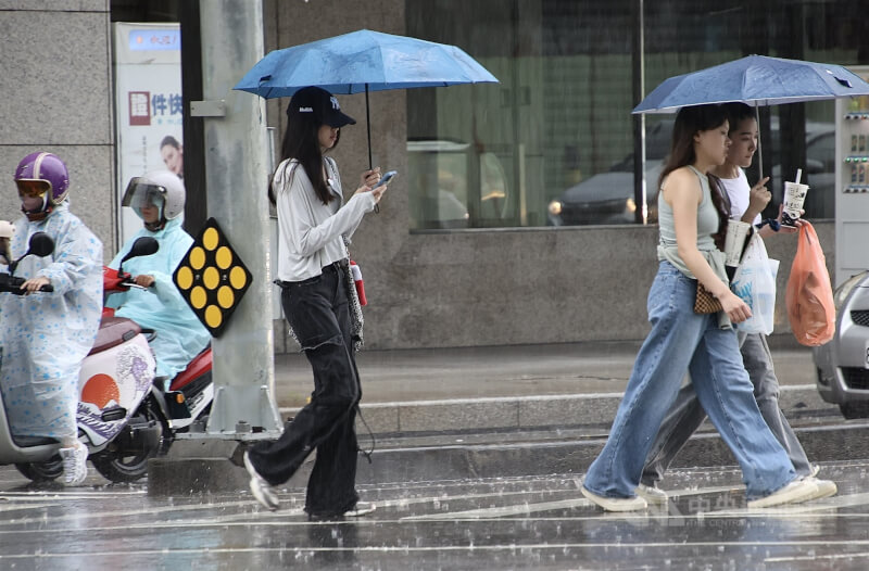 高雄苓雅區街頭民眾撐傘過馬路。(中央社檔案照片)