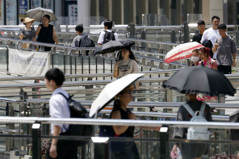 日本東京民眾撐傘遮擋烈日。 (共同社)