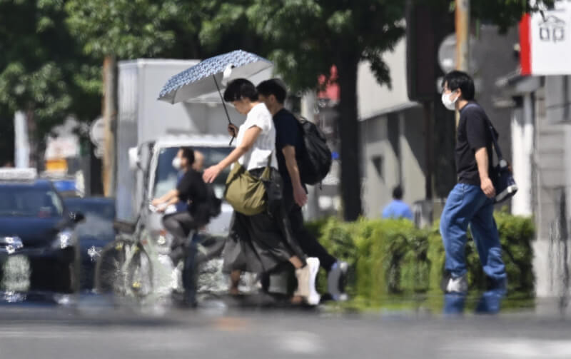 日本愛知縣名古屋市民眾30日撐傘遮陽。(共同社)