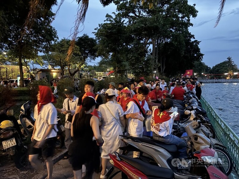 越南九二國慶前夕進行預演,封路柵欄旁人潮熱絡,穿戴國旗的民眾樂於欣賞停在大馬路上的戰車。中央社記者曾婷瑄河內攝 114年8月31日