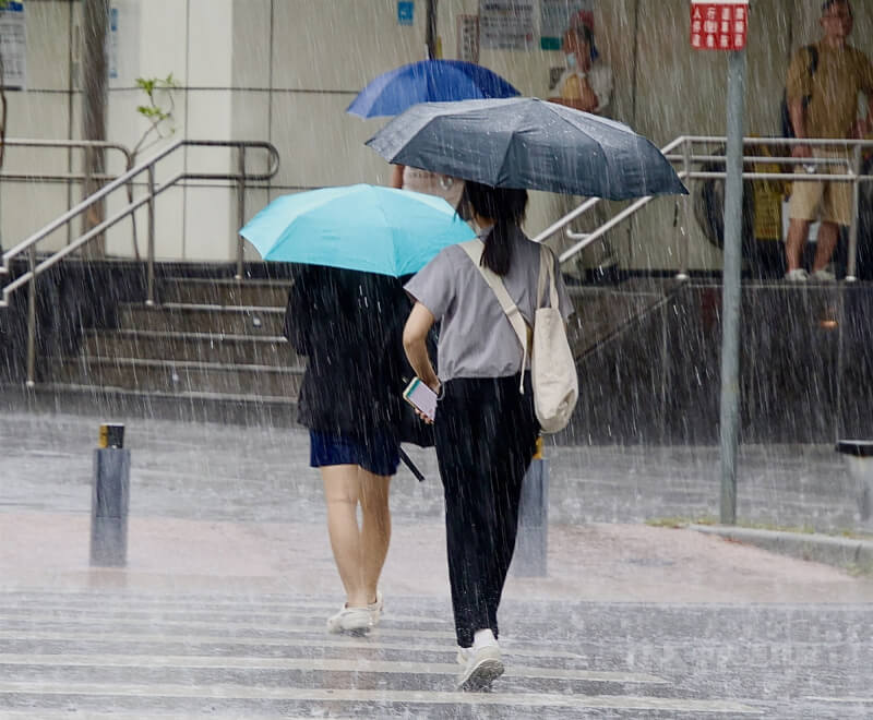 1日南部地區及中部山區有局部大雨發生機率。圖為高雄市苓雅區大雨行人紛紛撐起雨傘走避。(中央社檔案照片)