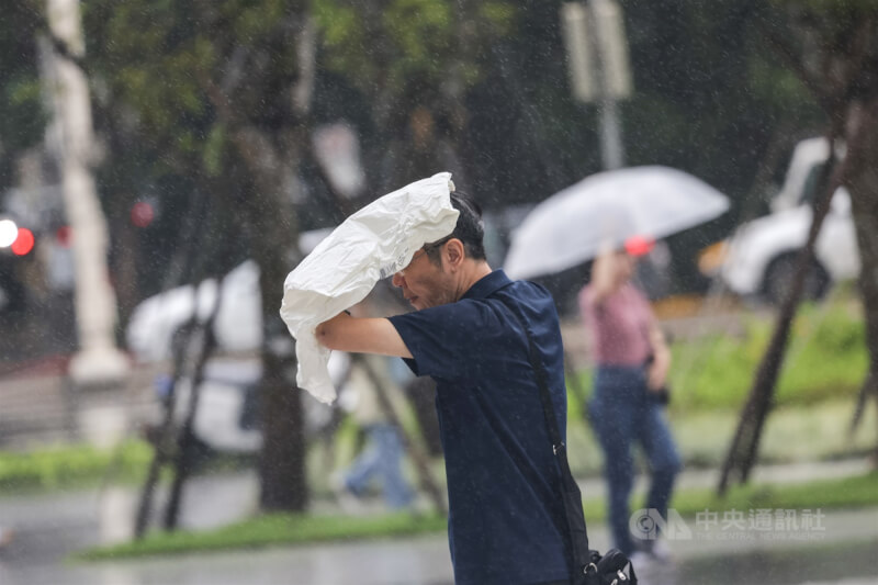 圖為台北市信義區行人以塑膠袋遮雨。(中央社檔案照片)