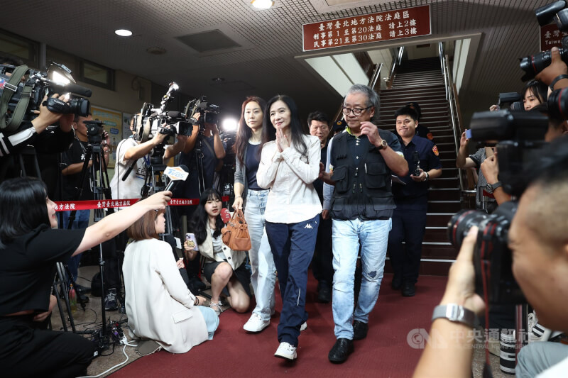 國民黨台北巿議員應曉薇(立者中白衣)5日晚間順利完成交保手續,隨後在律師陪同下離開北院,面對現場大批媒體提問,她僅雙手合掌、未多做回應。中央社記者王騰毅攝 114年9月5日
