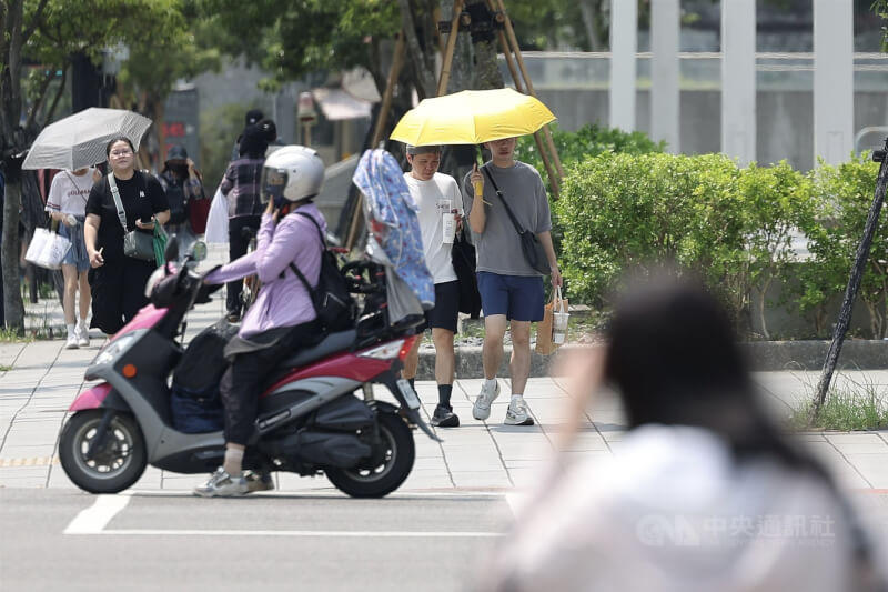 圖為台北市南港區街頭民眾撐傘遮陽,亦有騎車穿防曬外套避免曬傷。(中央社檔案照片)