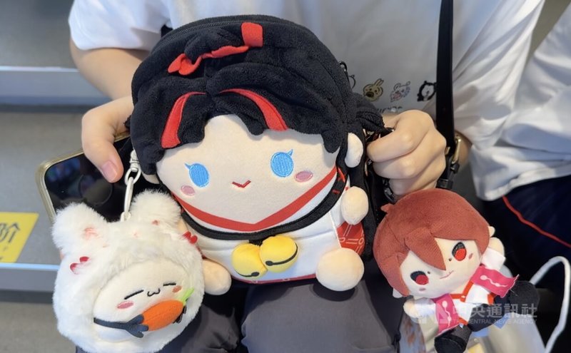 一位中國遊戲IP「陰陽師」的粉絲向記者介紹身上的周邊物品,包括包包與吊飾。圖攝於9月7日。中央社記者廖文綺上海攝 114年9月7日