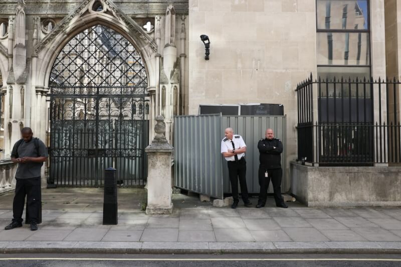 英國知名街頭塗鴉藝術家班克西8日公布倫敦皇家司法院外的新作品，但實體作品已被人拿黑布及柵欄遮住。（路透社）