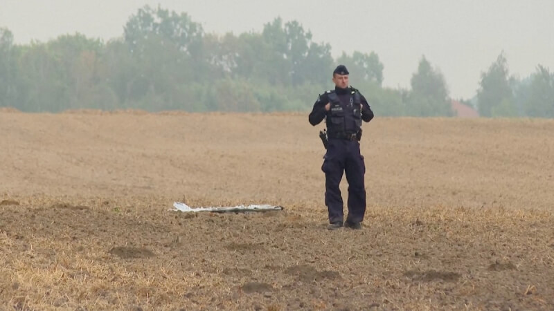 波蘭1名警察10日站在被擊落的俄羅斯無人機殘骸旁。（Polsat News via 路透社）