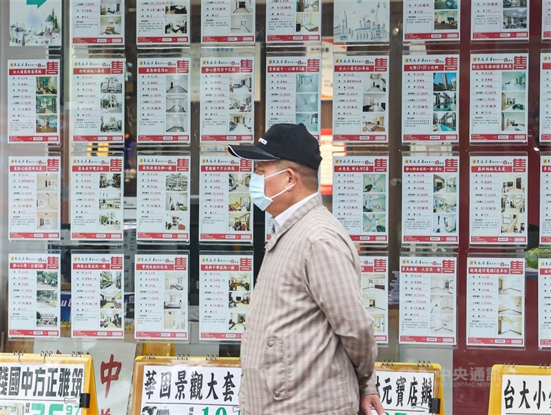 圖為民眾行經貼滿售屋廣告的房仲門市。 （中央社檔案照片）