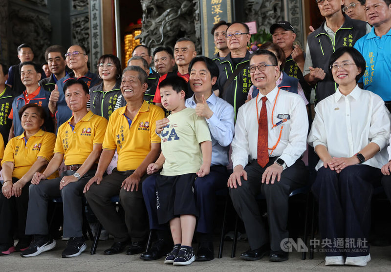 身兼民進黨主席的總統賴清德(坐者前右3)與民進黨秘書長徐國勇(前右2)、黨籍立委蘇巧慧(前右)13日赴板橋深丘福德宮參香,合照時親切抱著孩童留影。中央社記者趙世勳攝 114年9月13日