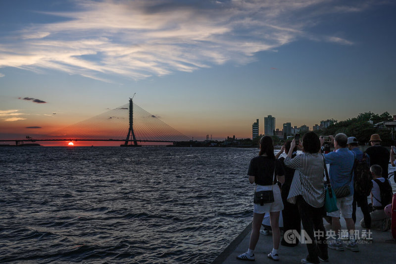 淡江大橋即將在115年通車,外界憂心會擋到淡水的夕陽美景。交通部公路局17日表示,當時會選擇單塔不對稱斜張橋的橋型設計,就是考量淡水夕照可以跟淡江大橋完美融合。圖為民眾傍晚在河岸邊捕捉淡江大橋與夕陽餘暉相互輝映的美景。中央社記者謝佳璋攝 114年9月17日