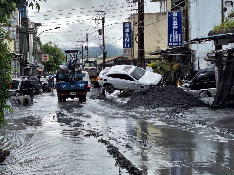24日上午淹水逐漸退去,有車輛隨著泥水漂流後列斜立於電線桿旁。(民眾提供)