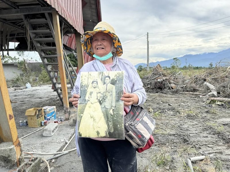 花蓮縣光復鄉東富村阿陶莫部落位在馬太鞍溪下游，日前堰塞湖溢流釀災，當地水淹逾1層樓高，76歲阿嬤李秀玉（圖）26日返家清理時，開心找回結婚紀念照。中央社記者張祈攝  114年9月26日