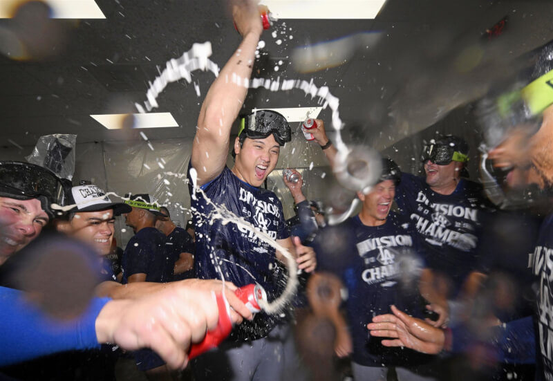 洛杉磯道奇25日連續第4年MLB國聯西區封王,大谷翔平(中)賽後與隊友在休息室開心慶祝。(共同社)