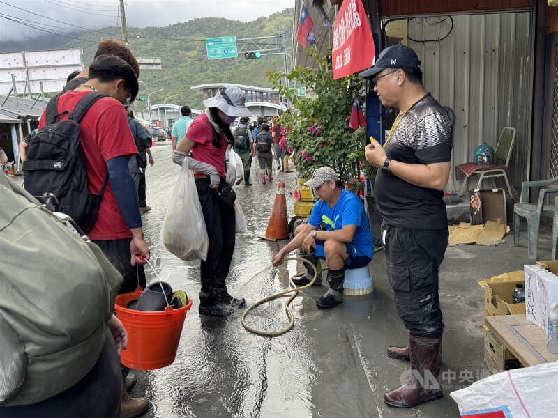 各地「鏟子超人」前進花蓮光復地區協助災民清理家園,30日有受災戶在車站前免費幫志工清洗雨鞋。中央社記者張祈攝 114年9月30日