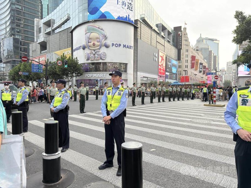 「十一」長假首日,在上海南京路步行街較大的十字路口,有成排武警(綠色制服者)站在馬路中央,形成人牆,管控人流與車流。中央社記者廖文綺上海攝 114年10月1日