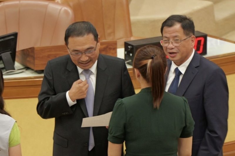 民進黨新北市議員陳乃瑜（背對者）1日在議會質詢時表示，日前救溺殉職消防員張敬謙父親交給她一封手寫陳情信，盼市府正視消防員工作環境，陳乃瑜並將陳情信交給市長侯友宜（左）。右為消防局長陳崇岳。（民進黨新北市議員陳乃瑜提供）中央社記者曹亞沿傳真　114年10月1日