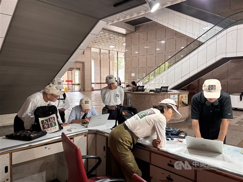 圖為人民作主志工團成員7月31日赴中選會領取公投案的電子連署系統認證碼，並一起研究如何使用筆電進入電子連署系統連署。（中央社檔案照片）