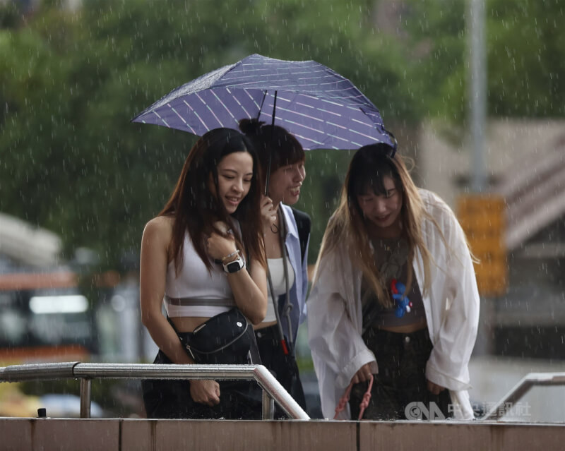 圖為台北車站前民眾與親友3人共撐一把傘。（中央社檔案照片）