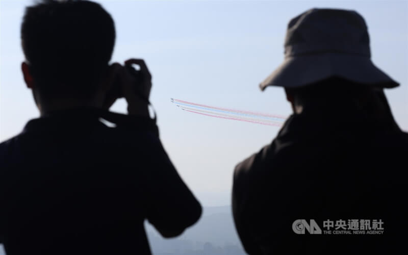 國軍8日清晨進行空中全兵力預演,空軍雷虎特技小組壓軸衝場,5架勇鷹高教機飛過台北市區上空施放彩煙,民眾一早也在觀機平台卡位,用相機捕捉畫面。中央社記者趙世勳攝 114年10月8日