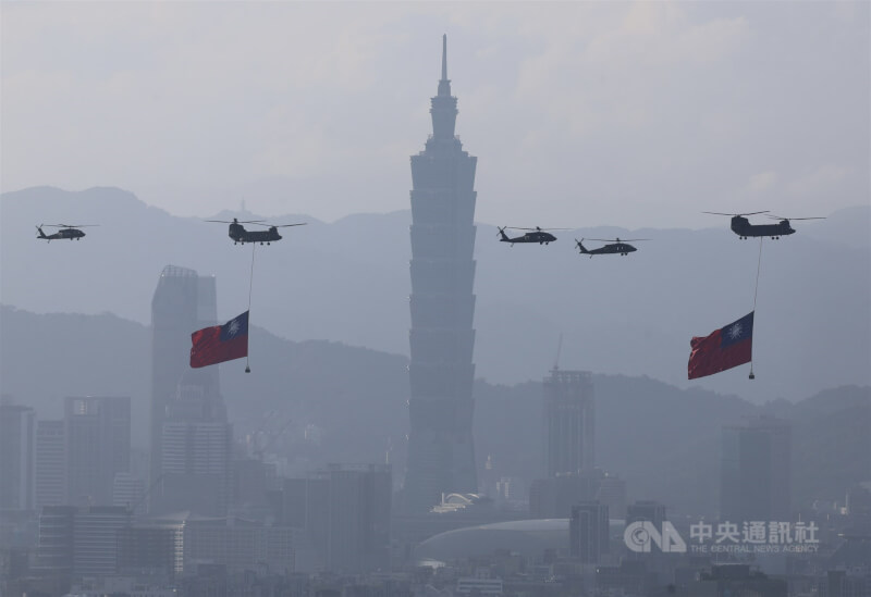 國軍8日上午進行空中全兵力預演,國旗機隊吊掛巨幅國旗飛越台北101大樓前,場面壯觀。中央社記者趙世勳攝 114年10月8日