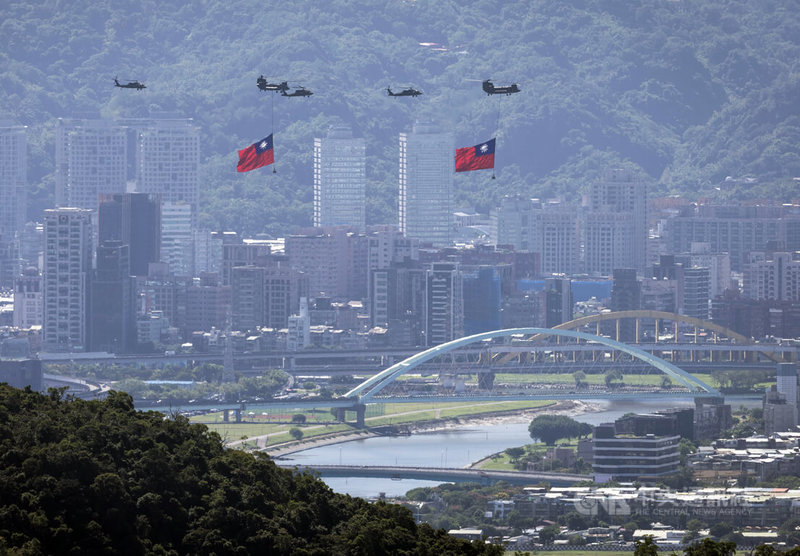 114年雙十國慶大會10日上午登場,由UH-60M黑鷹直升機伴飛懸掛著巨幅國旗的CH-47SD契努克運輸直升機,緩緩飛越台北市區上空。中央社記者趙世勳攝 114年10月10日