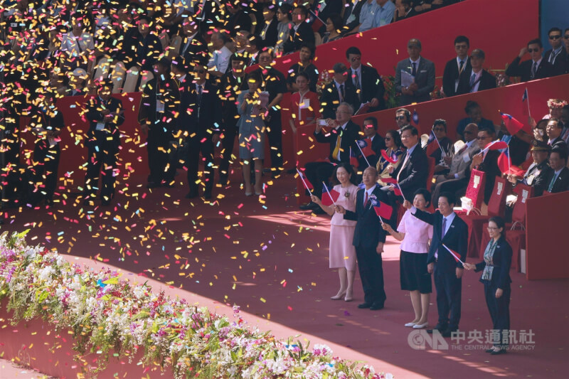 總統賴清德(前右2)與夫人吳玫如(前右3)、副總統蕭美琴(前右)、立法院長韓國瑜(前右4)與夫人李佳芬(前右5)向榮耀英雄車隊揮舞國旗致意。中央社記者徐肇昌攝 114年10月10日
