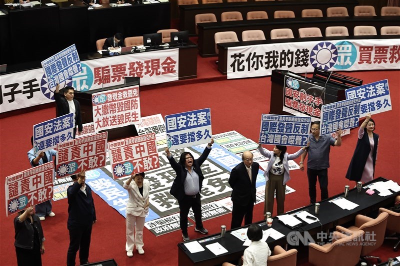 圖為民進黨團立委高舉看板質疑在野黨阻擋國安法案。(中央社檔案照片)