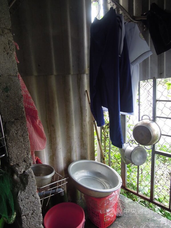 越南貧童黎氏黃鶯與媽媽住在一處簡陋鐵皮屋內,房間內沒有廁所,母女倆只能在毫無遮蔽的陽台上舀水洗澡。中央社記者吳欣紜攝 114年10月11日