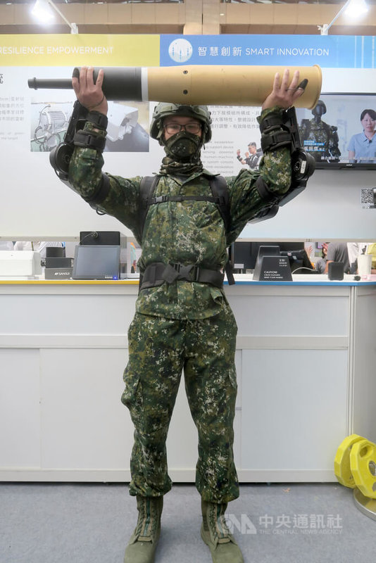 中科院16日於台灣創新技術博覽會展出軍用外骨骼系統,由研發人員穿戴軍用動力上肢外骨骼,輕鬆舉起20公斤重的105公厘戰車砲彈模型。中央社記者吳書緯攝 114年10月16日