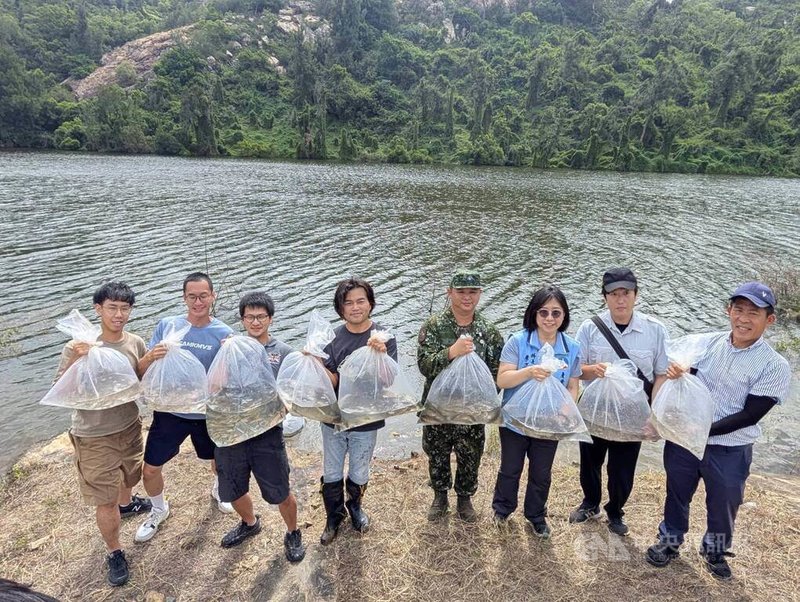 金門縣政府17日在擎天水庫舉辦「大鱗梅氏鯿野放活動」，產業發展處農林科長李姿維（右3）、再生魚坊執行長陳光耀（左4）等共同釋放大鱗梅氏鯿魚苗、高體鰟鮍等共800尾原生淡水魚。中央社記者吳玟嶸攝　114年10月17日