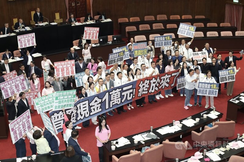 立法院會17日三讀通過「中央政府因應國際情勢強化經濟社會及民生國安韌性特別預算案」,其中包含普發現金1萬元預算新台幣2360億元。圖為朝野立委在議場內拿著手舉牌呼口號。中央社記者吳家昇攝 114年10月17日