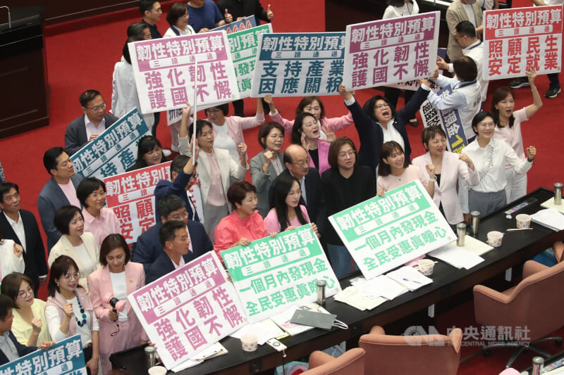 立法院會17日三讀通過「中央政府因應國際情勢強化經濟社會及民生國安韌性特別預算案」,其中包含普發現金1萬元預算新台幣2360億元。圖為民進黨立委拿著手舉牌呼口號。中央社記者吳家昇攝 114年10月17日