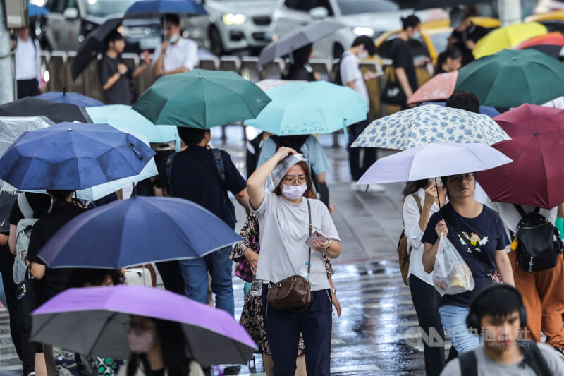圖為北市中正區民眾在雨中以塑膠袋遮擋快步過馬路。(中央社檔案照片)