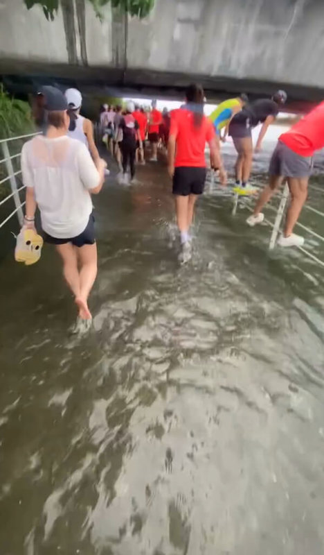 宜蘭縣冬山河水岸馬拉松19日清晨6時起跑,跑者經過傳藝大橋下時,發現水位已淹到自行車道,有選手選擇直接通過,也有選手脫下跑鞋涉水,還有部分選手攀爬欄杆通過。(讀者提供)中央社記者王朝鈺傳真 114年10月19日