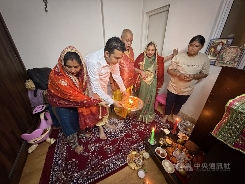印度人排燈節(Diwali)祭祀(Puja)中,家中女性長輩會帶頭吟唱經文,男性長輩會率大家將端著放有鮮花、油燈的盤子在神桌前「過爐」,祈求家庭成員都能獲得好運。中央社記者李晉緯新德里攝 114年10月21日