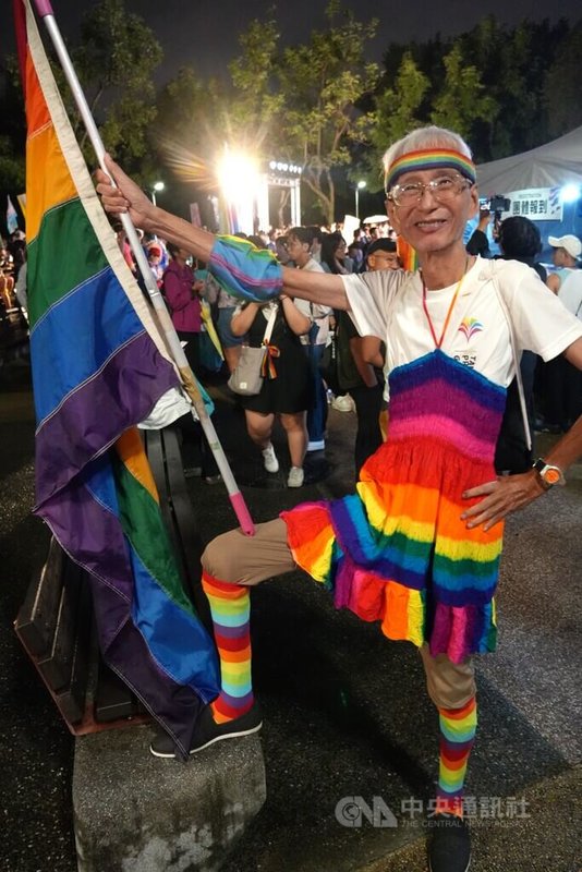 第7屆台灣跨性別遊行24日晚間在台北集結登場,台灣同志運動先驅祁家威(圖)身著彩虹服飾、手持大面彩虹旗到場聲援。中央社記者陳至中攝 114年10月24日