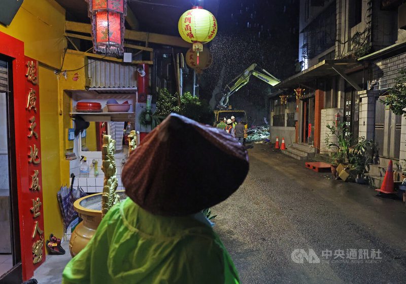 新北市新店區錦秀路49巷25日上午發生擋土牆坍塌,所幸撤離及時未釀傷亡,晚間現場持續進行清理、補強作業,附近民眾遠遠關切狀況。中央社記者趙世勳攝 114年10月25日