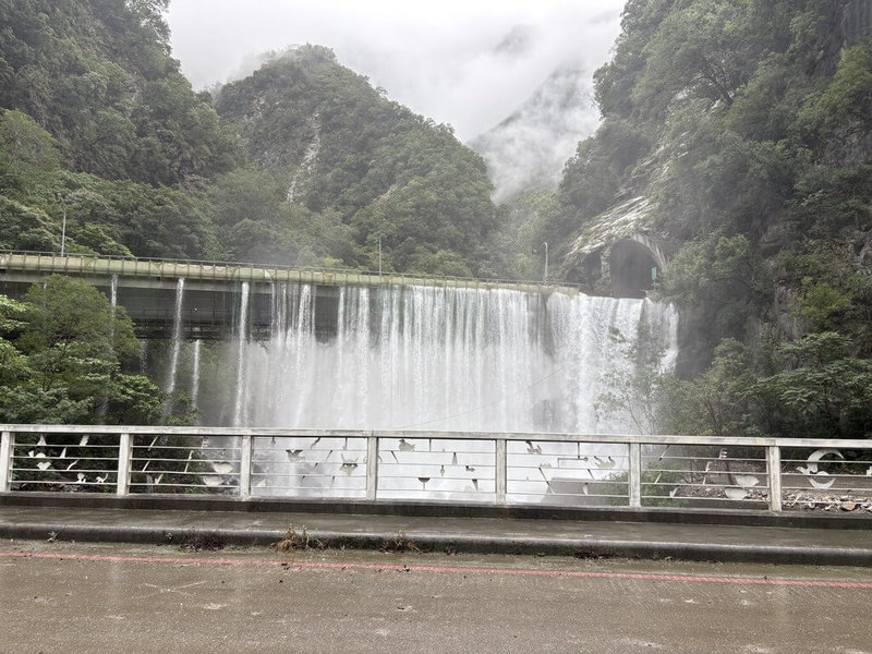 為加速降低燕子口堰塞湖水位與蓄水量,持續降挖壩體擴大引流,林保署增派2台500噸級大型挖土機進場將深槽線擴挖,整體通洪斷面擴大。圖為湖水漫過魯丹橋水簾狀況。(林業及自然保育署花蓮分署提供)中央社記者李先鳳傳真 114年10月28日
