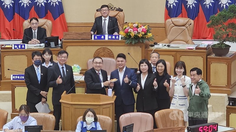 新北市議會市政總質詢，民進黨議員廖宜琨（立者左4）等多人請市長侯友宜（立者左3）吃豬肉漢堡，希望市府能多協助新北豬農渡過這波非洲豬瘟疫情。中央社記者王鴻國攝 114年10月29日