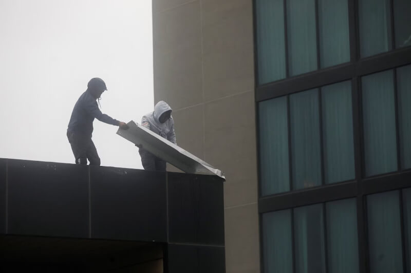 圖為颶風美莉莎登陸牙買加前,有飯店的工作人員正在屋頂拆除受損的排水溝。(路透社)