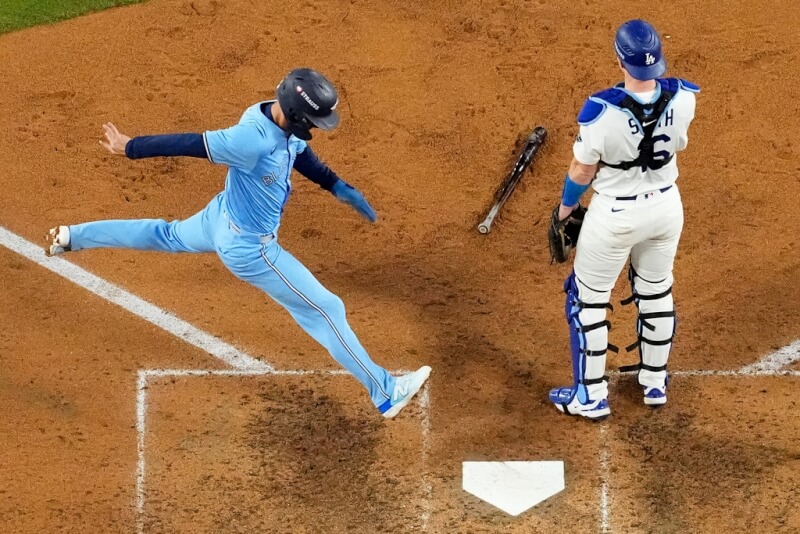 美國職棒世界大賽第5戰,多倫多藍鳥隊的安德烈斯吉梅內斯(左)在第七局越過洛杉磯道奇隊的捕手威爾史密斯(右)得分。(美聯社)