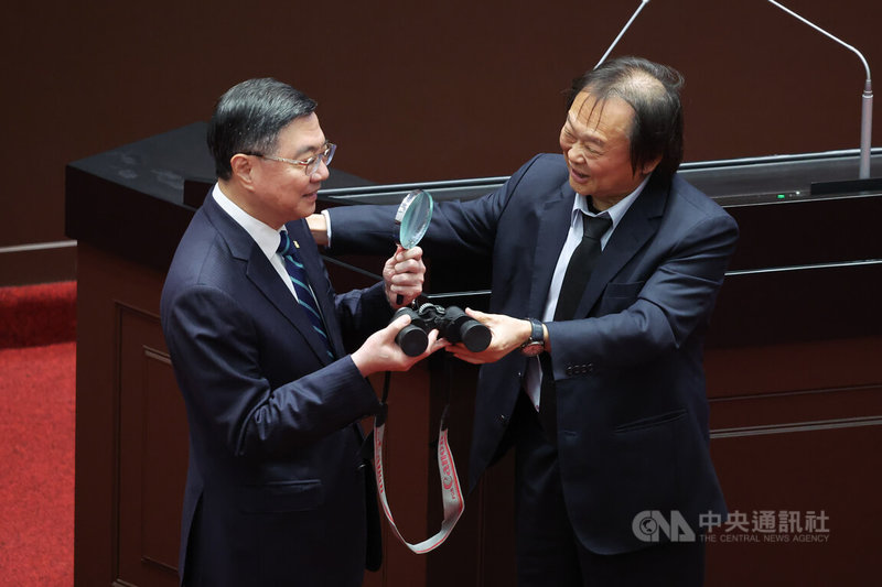 民進黨籍立委王世堅(右)31日於立法院質詢行政院長卓榮泰(左)前,特別拿出放大鏡及望遠鏡送給卓榮泰,呼籲施政要「高瞻遠矚、觀察細微」。中央社記者翁睿坤攝 114年10月31日