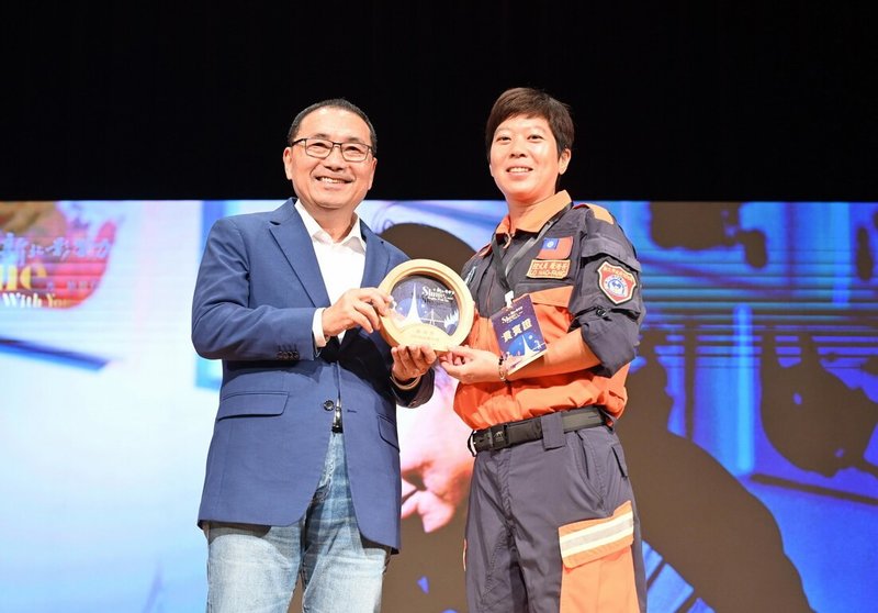 新北市政府1日舉辦2025新北影響力「城市共感x創藝漫談」分享會,並表揚10名影響力人物。新北市長侯友宜(左)出席並頒發獎座給入選影響力人物的消防局特搜大隊領犬員羅浩芳(右)。(新北市新聞局提供)中央社記者黃旭昇新北市傳真 114年11月1日