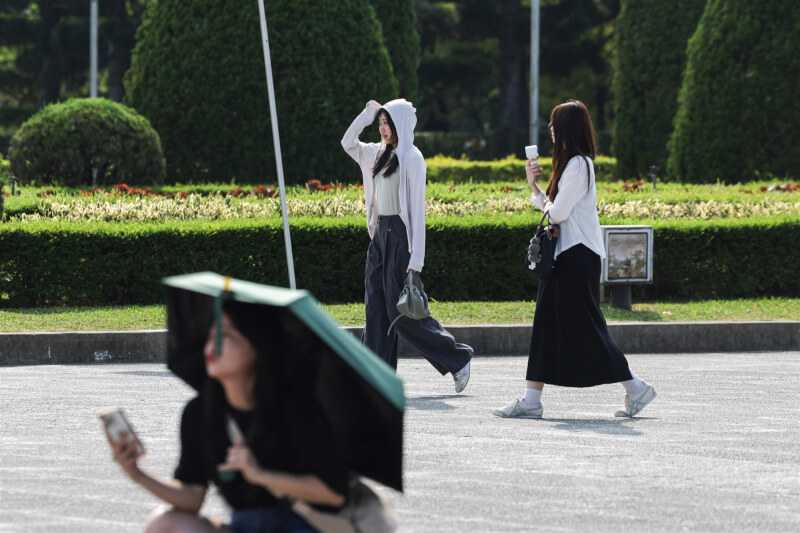 圖為台北市區下午豔陽高照，中正紀念堂園區遊客穿著防曬外套、撐傘遮陽。（中央社檔案照片）