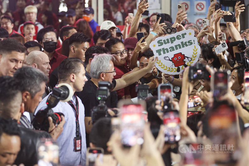 輝達(NVIDIA)執行長黃仁勳(中,持字卡者)8日現身2025年台積電運動會,黃仁勳在離去前與等候粉絲短暫互動,親切簽名。中央社記者鄭清元攝 114年11月8日