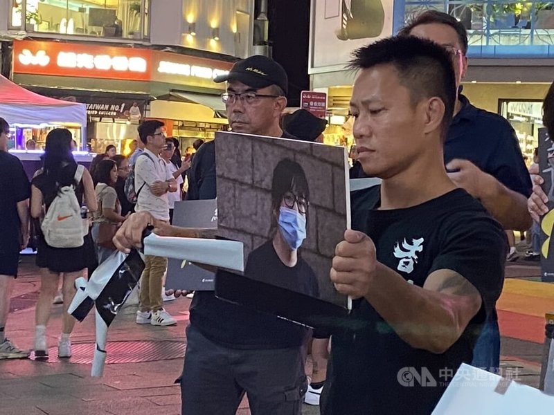台灣人權促進會等民間團體與香港支持者9日傍晚在台北西門町聚集,舉辦「台灣聲援李卓人、鄒幸彤被控煽動顛覆國家政權」活動。圖為在台流亡港人赴湯撕下由黑布膠帶貼著的鄒幸彤的牌子。中央社記者呂佳蓉攝 114年11月9日
