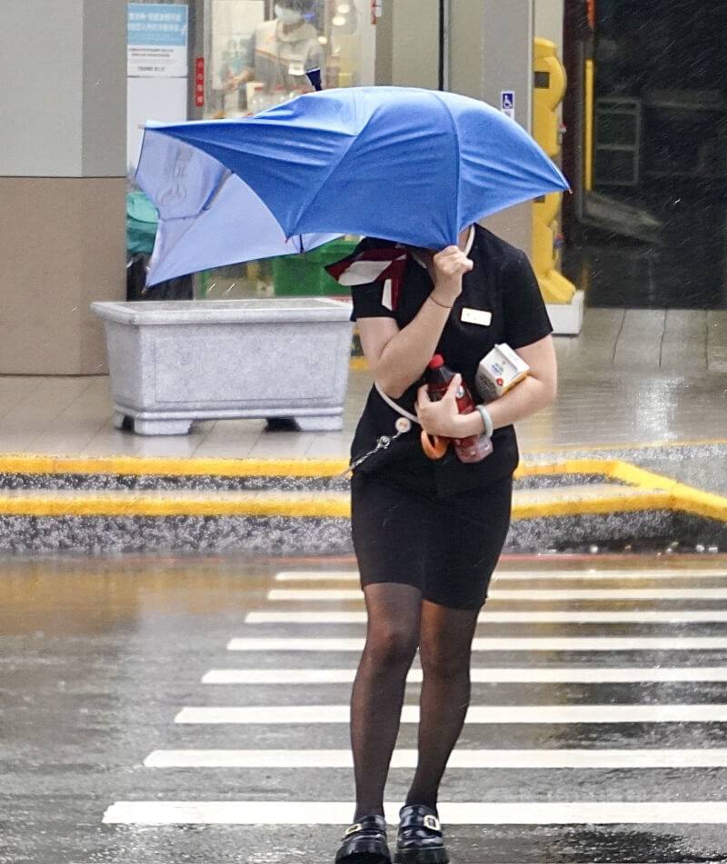 圖為高雄市街頭民眾冒著風雨前行。（中央社檔案照片）