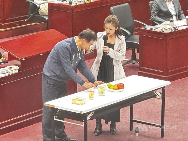 民進黨台北市議員洪婉臻（右）11日質詢時，在議場擺出多項水果，並表示，國小營養午餐提供飯後水果，因多數未切妥，讓學生不願食用，要求市府研議增加截切水果選項，並針對小學先試辦。中央社記者劉建邦攝　114年11月11日